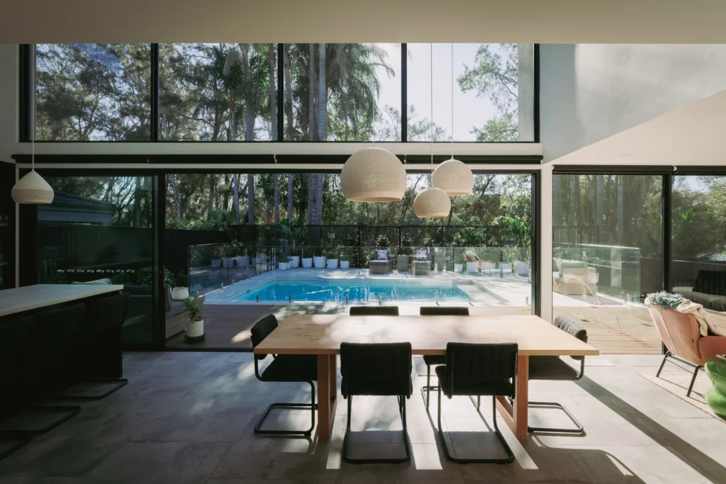 Modern dining space featuring natural light, pool views, and contemporary furnishings